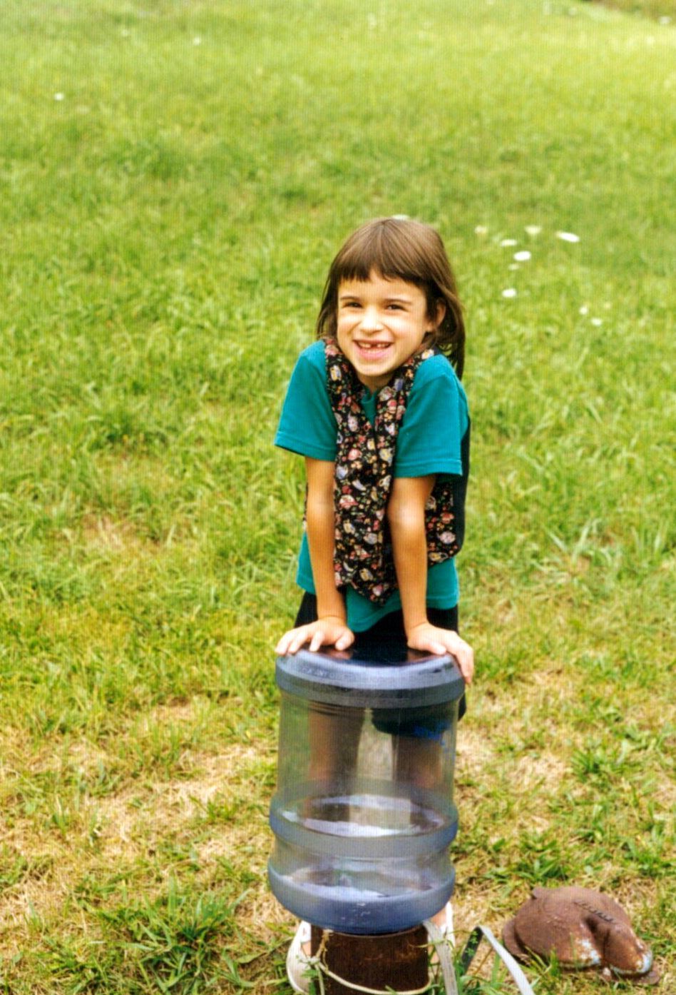 A young Beal leans on a 5 gallon jug of water that's turned upside down in the well.